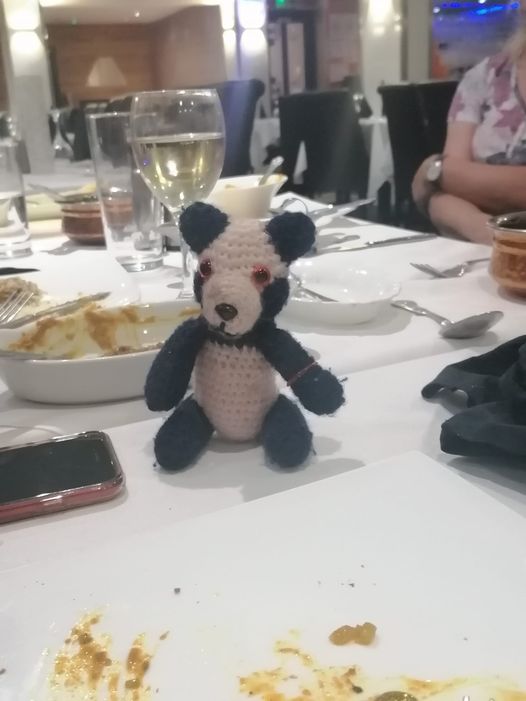 Panda on a table with wine glasses and plates